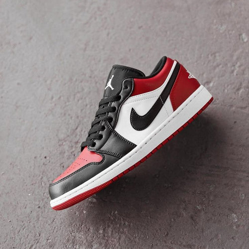 Black, red, and white sneaker with Nike logo on a gray background